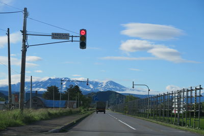 Road signal over road against sky