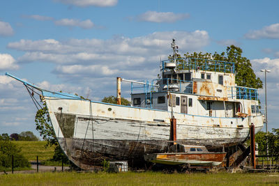 Abandoned boat moored on shore against sky