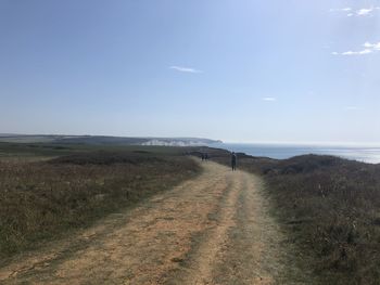 Scenic view of road by sea against sky