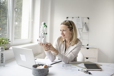 Smiling female technician holding electronic equipment at office