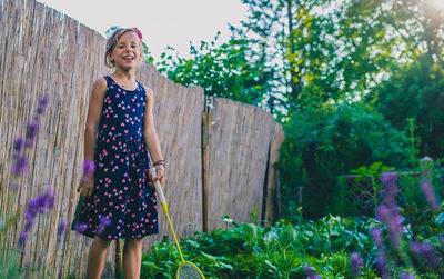 Portrait of girl holding badminton racket while standing at yard