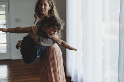 Daughter and mother playing airplane in natural light studio