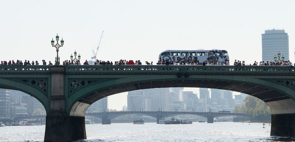 Bridge over river in city against clear sky