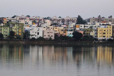 Buildings by lake against clear sky