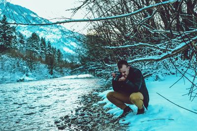 Man photographing through camera at lake during winter