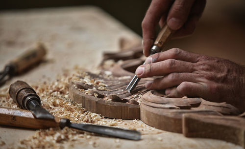 Cropped hands carving on wood in workshop