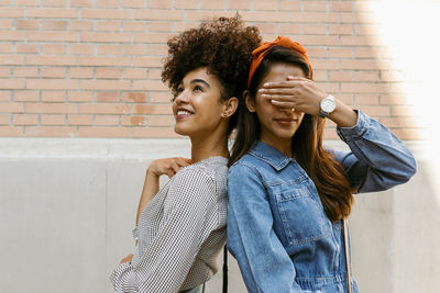 Portrait of a smiling young woman against wall