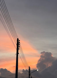 Low angle view of electricity pylon against sky during sunset