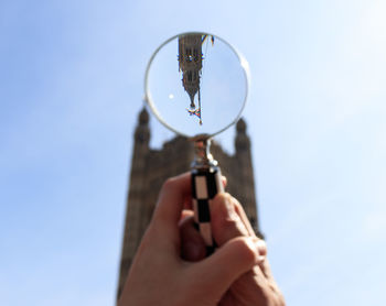 Low angle view of person hand against sky