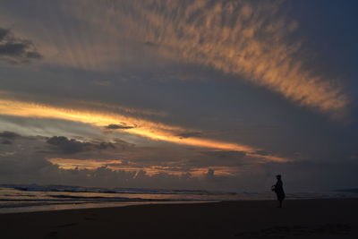 Silhouette of people on beach at sunset