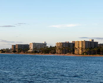 Sea by buildings against sky in city