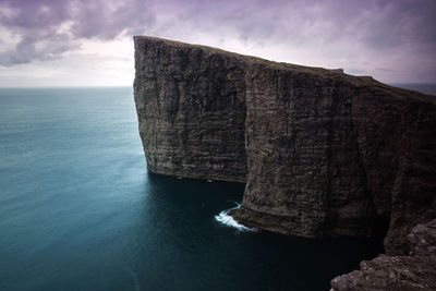 Rock formation by sea against sky