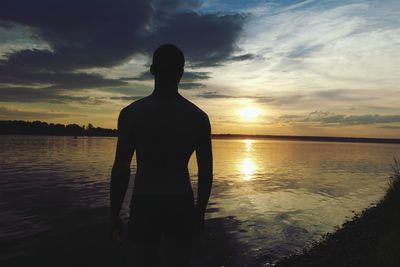 Silhouette man standing by sea against sky during sunset