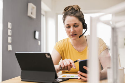 Female entrepreneur video conferencing through digital tablet while sitting at desk