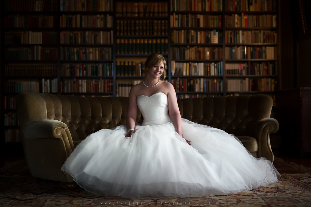 one person, young adult, portrait, indoors, looking at camera, full length, young women, adult, front view, fashion, smiling, women, happiness, dress, furniture, beautiful woman, celebration, real people, bookshelf, hairstyle