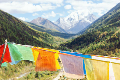 Multi colored flags hanging on mountain against sky