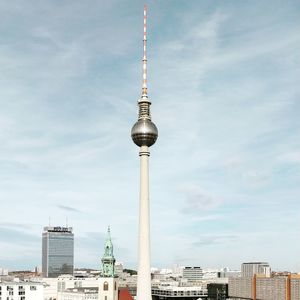 Communications tower in city against sky