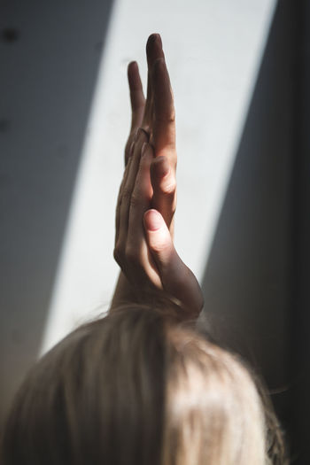 MIDSECTION OF WOMAN HAND WITH SHADOW ON WALL