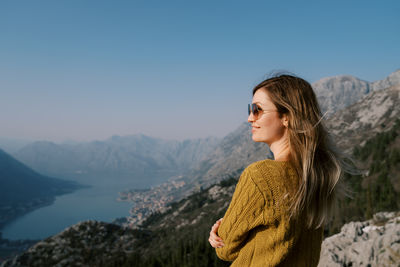 Side view of young woman standing against mountain