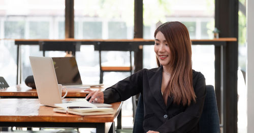Young woman using phone while sitting on table