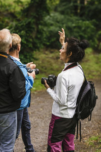 Female instructor gesturing while explaining senior men during photography course