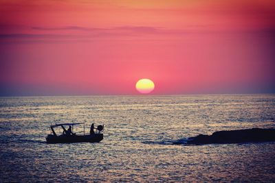 Silhouette boat in sea against sky during sunset