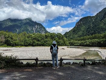 Rear view of men looking at mountains against sky