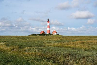 Lighthouse on field against sky