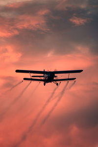 Low angle view of airplane against sky during sunset