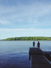 Men standing on lake against sky