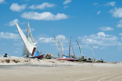 Sailboats moored on beach against sky