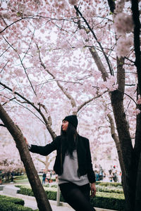 Rear view of woman standing by pink flowers in park