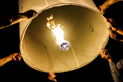 Low angle view of people lighting lantern at night