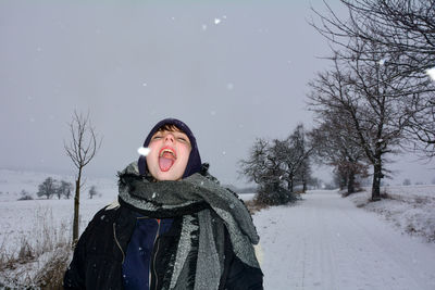 Girl in nature, catches snowflakes with her tongue with a way in the background