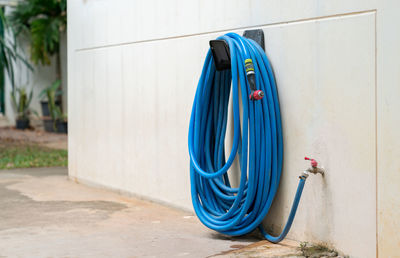 Blue garden hose reel on wall for water the plants in front yard.