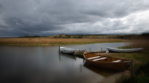 Boat moored in lake against sky