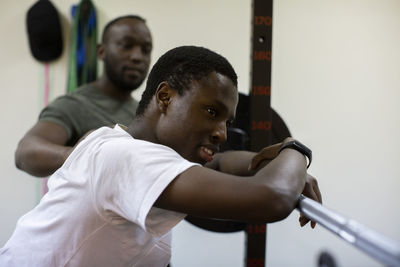 Tired athlete leaning on barbell in gym