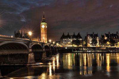 Illuminated bridge over thames river with big ben in city at night