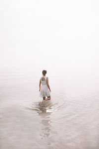 Full length of shirtless man in sea against clear sky