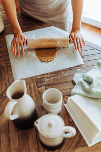 Hands rolling dough for cookies on table, top view