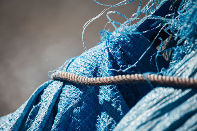 Close-up of rope on blue torn tarpaulin