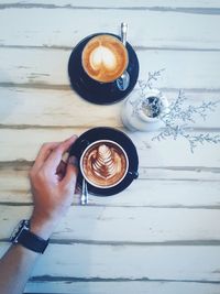 Cropped image of hand holding coffee at table
