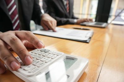 Midsection of man using smart phone on table