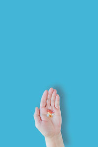 Close-up of hand over blue background