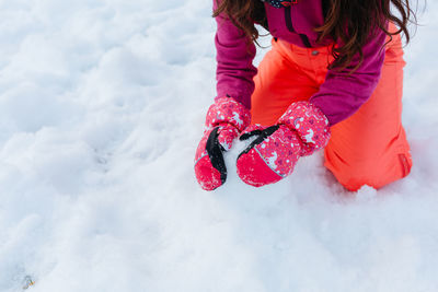 Close up on hands in gloves of the girl playing with snow