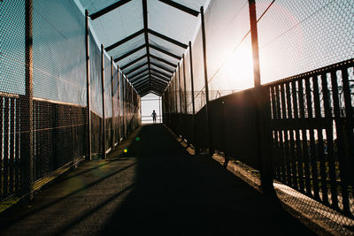 Silhouette boy standing on footbridge during sunset