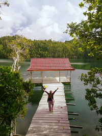 Rear view of woman by lake against sky