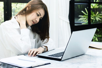 Young woman using phone while sitting on table