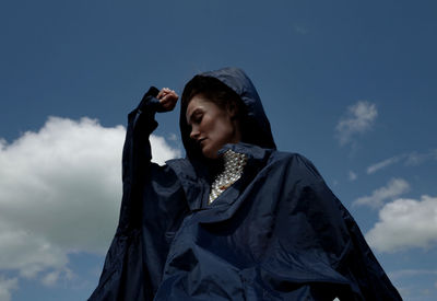 Portrait of woman photographing against sky