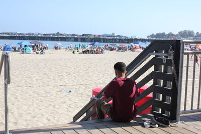 People sitting on beach against clear sky